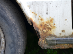 Severely rusted car body near wheel.