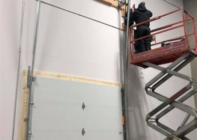 Technician installing garage door from lift.