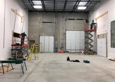 Workers installing doors in commercial warehouse interior.