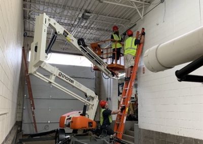 Construction crew using lift and ladders indoors.
