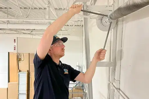 Technician repairing garage door torsion spring.