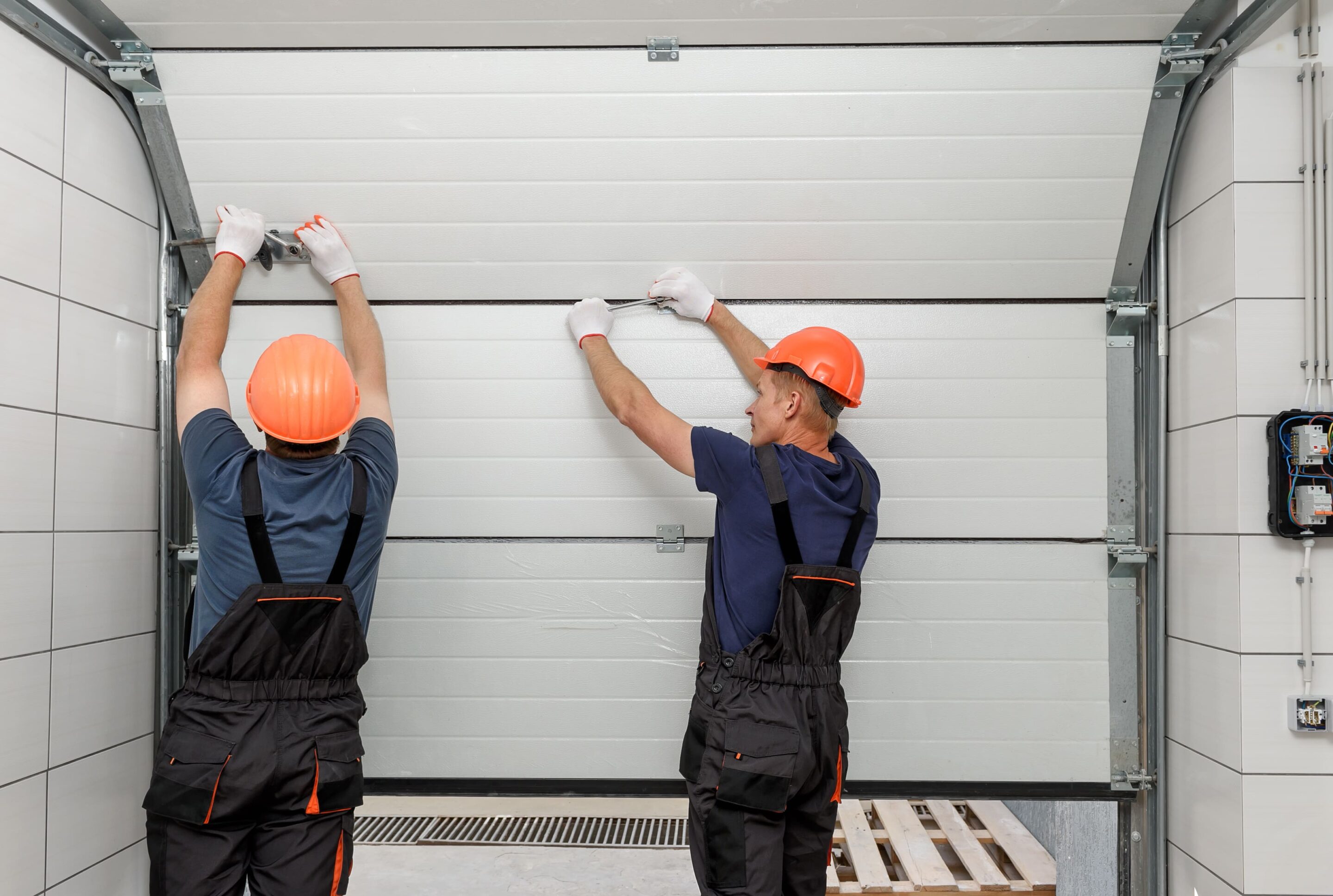 Technician installing garage door inside workshop.
